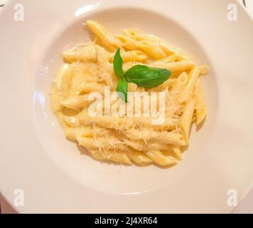 Draufsicht auf das traditionelle italienische Gericht Penne Pasta mit geriebenem Käse und Basilikum. Stockfoto