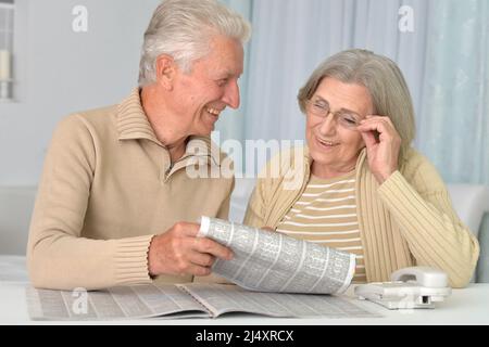 Seniorenpaar lacht mit Zeitung zu Hause Stockfoto