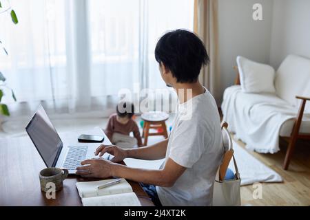 Japanischer Mann, der von zu Hause aus mit Kind arbeitet Stockfoto