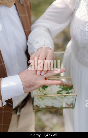 Die Braut legt den Ehering auf den Finger des Bräutigams Stockfoto