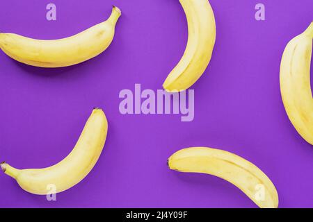 Reife gelbe Bananen auf violettem Hintergrund, Textur Stockfoto