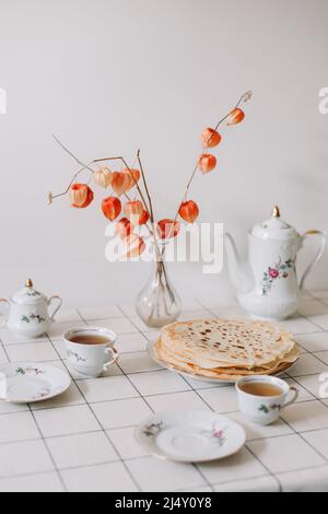 Ein Set aus Porzellankaffee und -Tee mit Tassen, Tassen und Tellern auf einem Tisch. Stockfoto