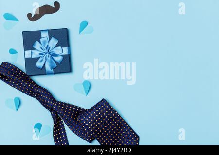 Väter Tag Konzept. Krawatte Schnurrbart Box mit einem Geschenk mit Papier Herzen auf einem blauen Hintergrund. Stockfoto