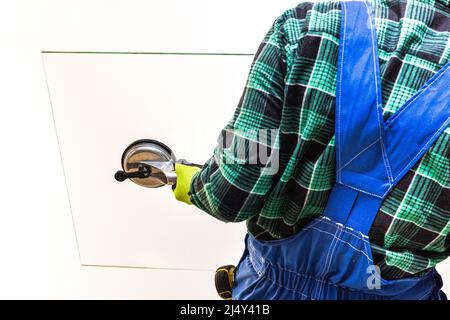 Ein Glasarbeiter hält mit einem speziellen Sauger eine dicke Glasscheibe in den Händen Stockfoto