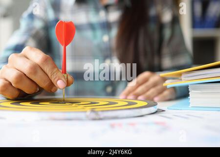 Person hält Dartpfeil in der Mitte des Nahspiels von Darts Stockfoto