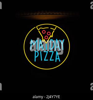 Neon Mayday Pizza Schild, das nachts vor einem Pizzeria-Eingang in Bratislava, Slowakei, leuchtet. Stockfoto