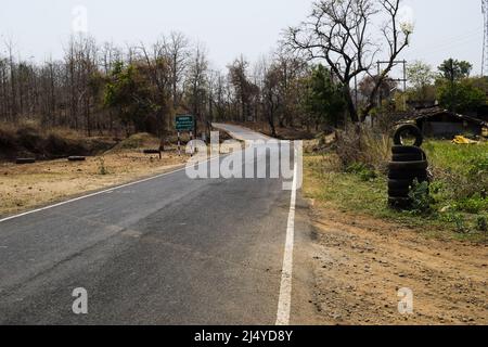 Highway Road auf Ghat Berggebiet im Wald in madhya pradesh mit weißer Linie Markierung auf beiden Seiten der Straße und getrockneten Bäumen. Reifengeschäft in der Nähe von dhaba mot Stockfoto