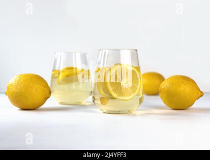 Zwei Gläser mit Limonade und Zitronenscheiben auf einem weißen Tisch. Konzept des nationalen Limonade-Tages. Stockfoto