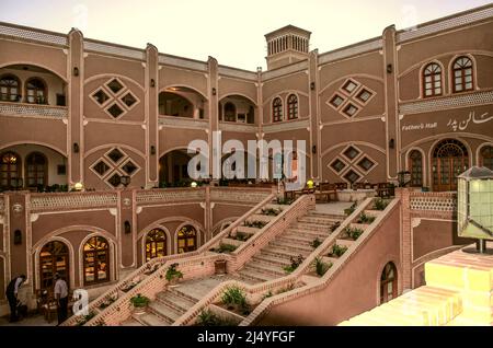 Yazd, Iran, 19. Februar 2021: Eine Treppe führt in das untere Stockwerk der Innenfassade in einem Café mit Tischen und Stühlen inmitten von Blumen beim PAPA Hote Stockfoto