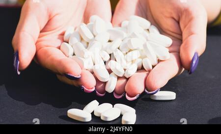 Arzt mit Pillen in der Hand. Draufsicht auf Haufen weißer Pillen in den Händen der Frauen. Stockfoto