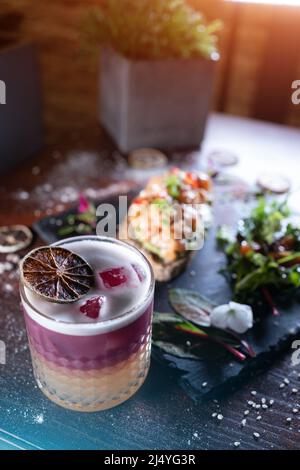 Frischer, stilvoller, rosafarbener Grapefruit-Cocktail mit Schaumstoff und Sandwich Stockfoto