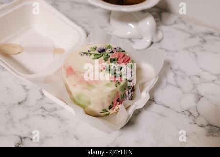 Kleine Bento-Torte, verziert mit Zuckerblumen als Geschenk für den Urlaub. Kuchen in einer Schachtel für eine Person Stockfoto