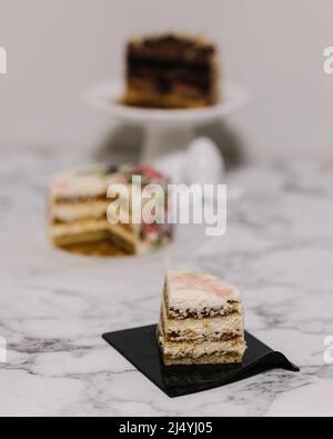 Scheibe Tiramisu-Bento-Kuchen. Präsentation des Kuchens im Abschnitt. Süßes Dessert für eine Person. Kleiner Geburtstagskuchen. Hintergrund von anderen Bento-Kuchen Stockfoto