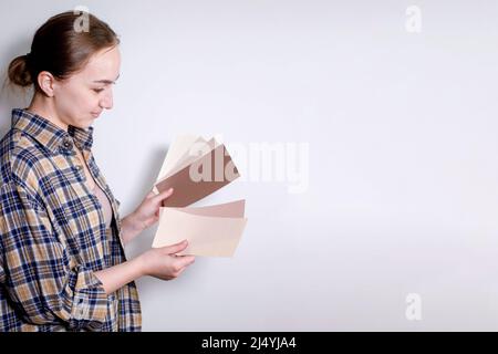 Die junge Frau hält Farbproben für die Wand in der Hand Stockfoto