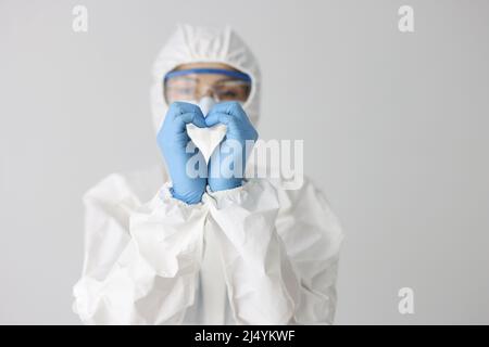Der Arzt in Schutzanzug macht mit den Händen eine Herzbewegung Stockfoto