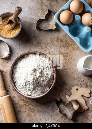 Der Prozess des Backens, Kochen flach legen. Mehl in der Schüssel, Eier, Zucker, Milch auf braunem rustikalem Hintergrund. Draufsicht Stockfoto