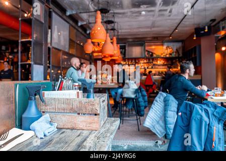 Touristen, die im beleuchteten Restaurant im Resort in der Alpenregion essen Stockfoto