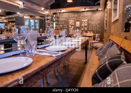 Nahaufnahme der Tische und Bänke im beleuchteten Restaurant des Resorts Stockfoto