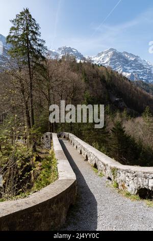 Riedern, Kanton Glarus, Schweiz, 13. April 2022 Historische alte Steinbrücke in einem Wald über eine kleine Schlucht Stockfoto