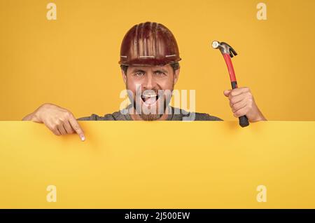 Glücklicher Tag der Geburt. Reifer Mann im Helm mit Hammer. builder Point Finger auf Kopie Raum Stockfoto