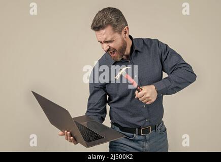 Wütend Mann brechen Laptop schlagen Notebook mit Hammer grauen Hintergrund, Computer Wut Stockfoto