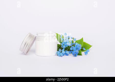 Weiße Creme-Glas und blaue Vergiss-mich-nicht Blume. Natürliche Hautpflege kosmetisches Konzept. Nahaufnahme. Stockfoto