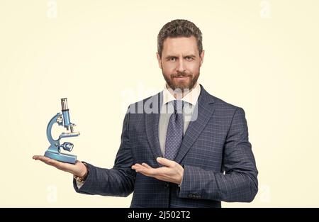Unternehmer Mann in Anzug präsentiert moderne Mikroskop isoliert auf weißen, wissenschaftlichen Methode. Stockfoto