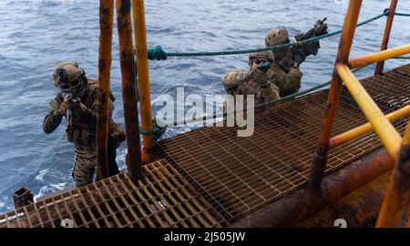 Ein Mitglied der Philippine Navy Special Operations Group, der U.S. Navy SEAL with Special Warfare Group, und ein australischer Operator mit 2. Commando Regiment führen zusammen während der Übung Balikatan 22 vor der Küste von Palawan, Philippinen, Seesicherheitsoperationen durch, 7. April 2022. Balikatan ist eine jährliche Übung zwischen den Streitkräften der Philippinen und dem US-Militär, die darauf ausgerichtet ist, bilaterale Interoperabilität, Fähigkeiten, Vertrauen und Zusammenarbeit zu stärken, die auf jahrzehntelangen gemeinsamen Erfahrungen aufgebaut wurden. Balikatan, Tagalog für „von der Schulter zur Schulter“ ist eine langjährige bilaterale Übung zwischen dem P Stockfoto