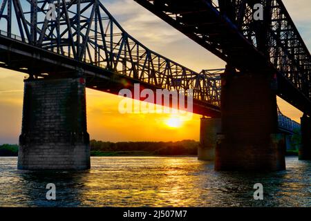 Die Sonne untergeht über der Küste von Arkansas an der Harahan- und Frisco-Brücke am Mississippi River bei Memphis, Tennessee. Stockfoto