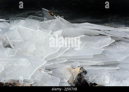 Platten aus gebrochenem Seeglas am Seeufer, die von starken Winden gebildet wurden und wiederholte brechende Wellen im Wasser verursachen Stockfoto