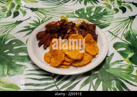 Dominikanische Küche bekannt als Chicharron De Pollo Con Chuleta Frita Y Tostones Stockfoto