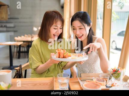 Glückliche Freundinnen, die gemeinsam im Restaurant zu Mittag essen Stockfoto