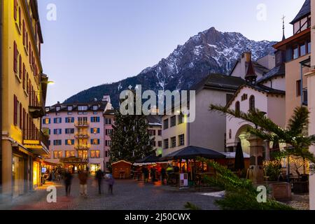 Abendansicht der Brig-Glis Straße mit Weihnachtsbaum auf dem Hintergrund der Alpengipfel Stockfoto