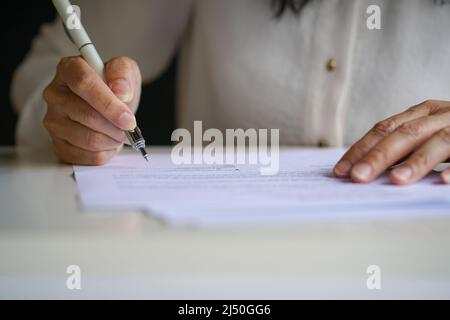 Hand der Geschäftsfrau unterzeichnen auf Papier Dokument. Nahaufnahme, Platz kopieren. Stockfoto