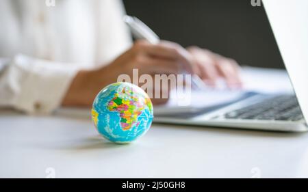 Nahaufnahme der Welt mit einer Geschäftsfrau und einem Computer-Laptop im Hintergrund. Speicherplatz kopieren. Stockfoto