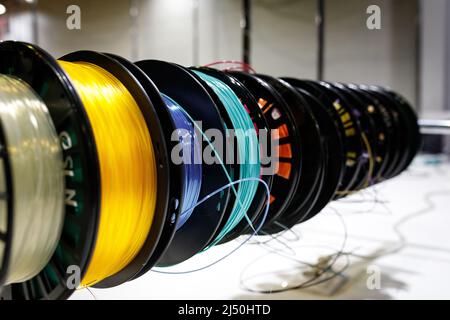 Seitenansicht von bunten Kunststoff-PLA- und ABS-Spulen mit Filament für den Druck auf einem 3D-Drucker. Stockfoto