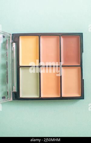 Schminkpalette mit bunten Concealern auf minzfarbenem Hintergrund. Selektiver Fokus. Stockfoto