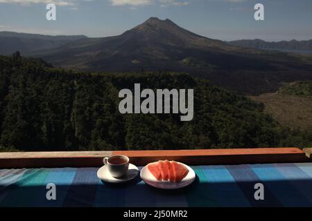 Wassermelone und Tee auf einem Restauranttisch im Hintergrund des Mount Batur in Kintamani, Bangli, Bali, Indonesien. Stockfoto