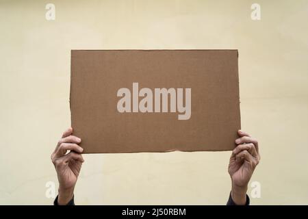 Hand hält leere Pappplakette hoch Stockfoto