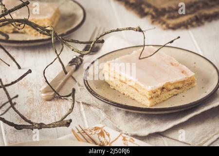 Stück gedeckter Apfelkuchen mit Zuckerguss auf rustikalem Holzhintergrund. Harmonisches Farbkonzept in Beigetönen Stockfoto