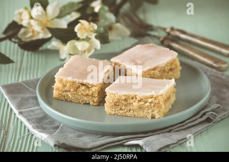 Stücke von gedeckten Apfelkuchen mit Zuckereier auf hellgrünem Hintergrund, verziert mit blühenden Zweigen Stockfoto