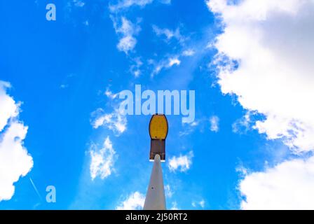 Straßenlampe am blauen Himmel an einem sonnigen Tag mit vielen weißen Wolken Stockfoto