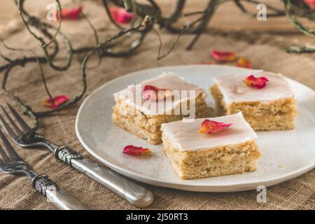 Stücke von gedeckten Apfelkuchen mit Zuckereier und Rosenblättern auf einem rustikalen Holzhintergrund, verziert mit Ästen Stockfoto