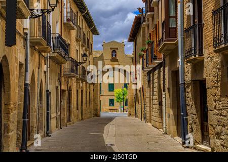 Rustikale mittelalterliche Steinhäuser in einer Straße mit einem Torbogen, der zu einem platz in Olite, Spanien führt, der für ein herrliches Schloss des königlichen Palastes berühmt ist Stockfoto