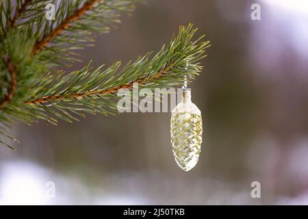 Weihnachtsspielzeug in Form eines Kegels, das in der Natur an einem Weihnachtsbaum hängt. Hochwertige Fotos Stockfoto
