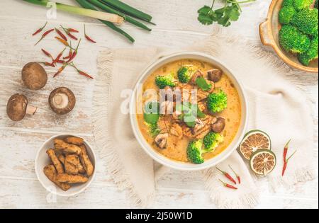 Vegane Tom Kha Gai Suppe mit verschiedenen Gemüsesorten und gerösteten Soja-basierten Fleischersatzstoffen, Draufsicht Stockfoto