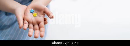 Teilansicht des verschwommenen Mädchens mit blauen und gelben Sternen auf grauem Hintergrund, Banner Stockfoto