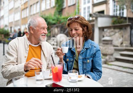 Porträt eines glücklichen älteren Ehepaares, das im Café im Freien sitzt und Kaffee getrunken hat. Stockfoto