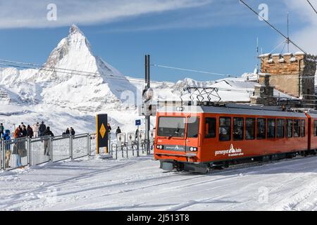 Gornergrat, Zermatt, Schweiz - 12. November 2019: Rote Seilbahn auf der Schneerbahn an der Bergstation mit Hintergrund des Matterhorn-Gipfels in w Stockfoto