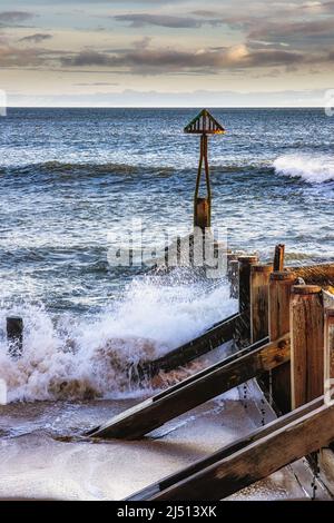 Wellen schlagen die alte hölzerne Groyne in Seaton Sluice, Northumberland, Großbritannien Stockfoto